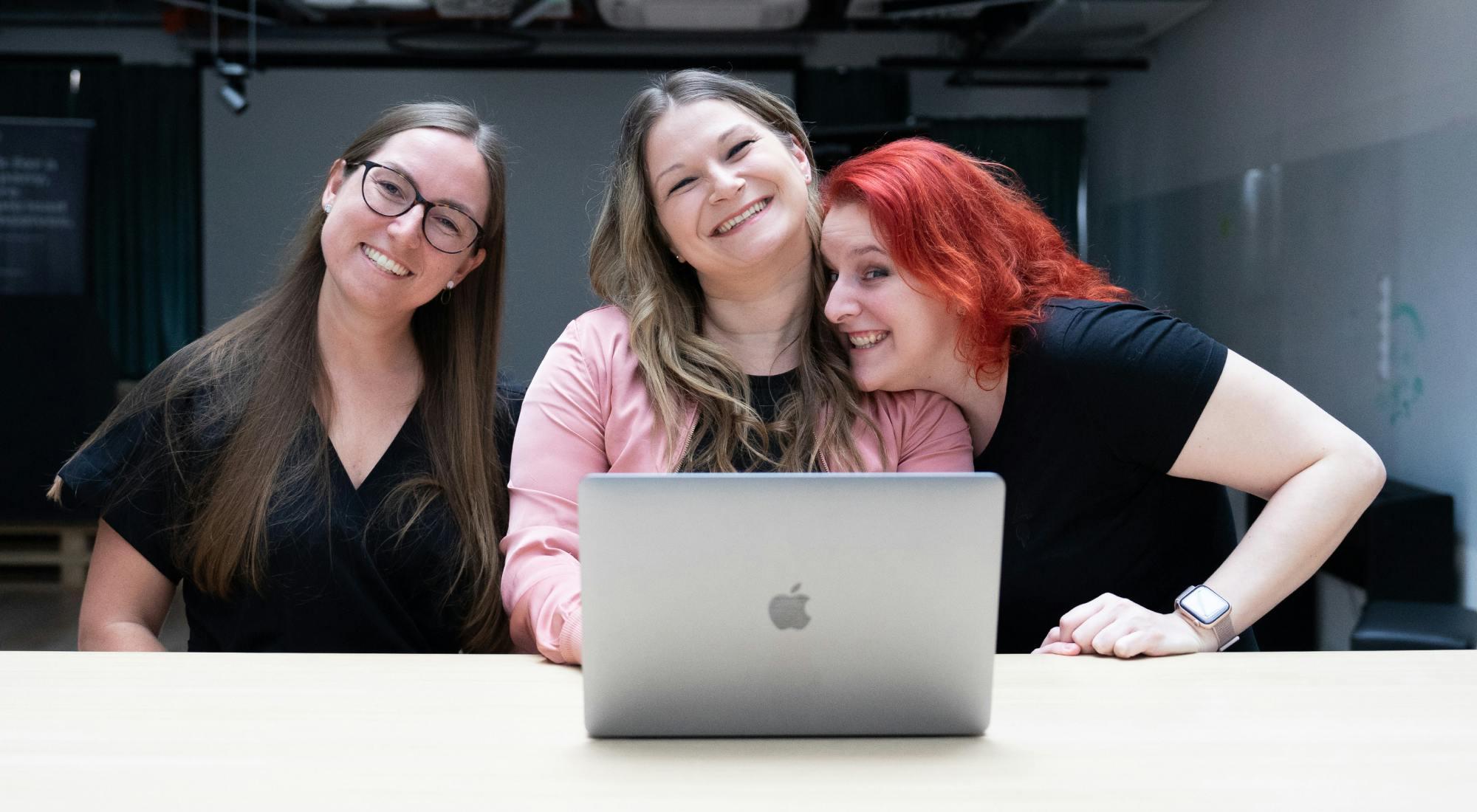 Three smiling women working by the computer